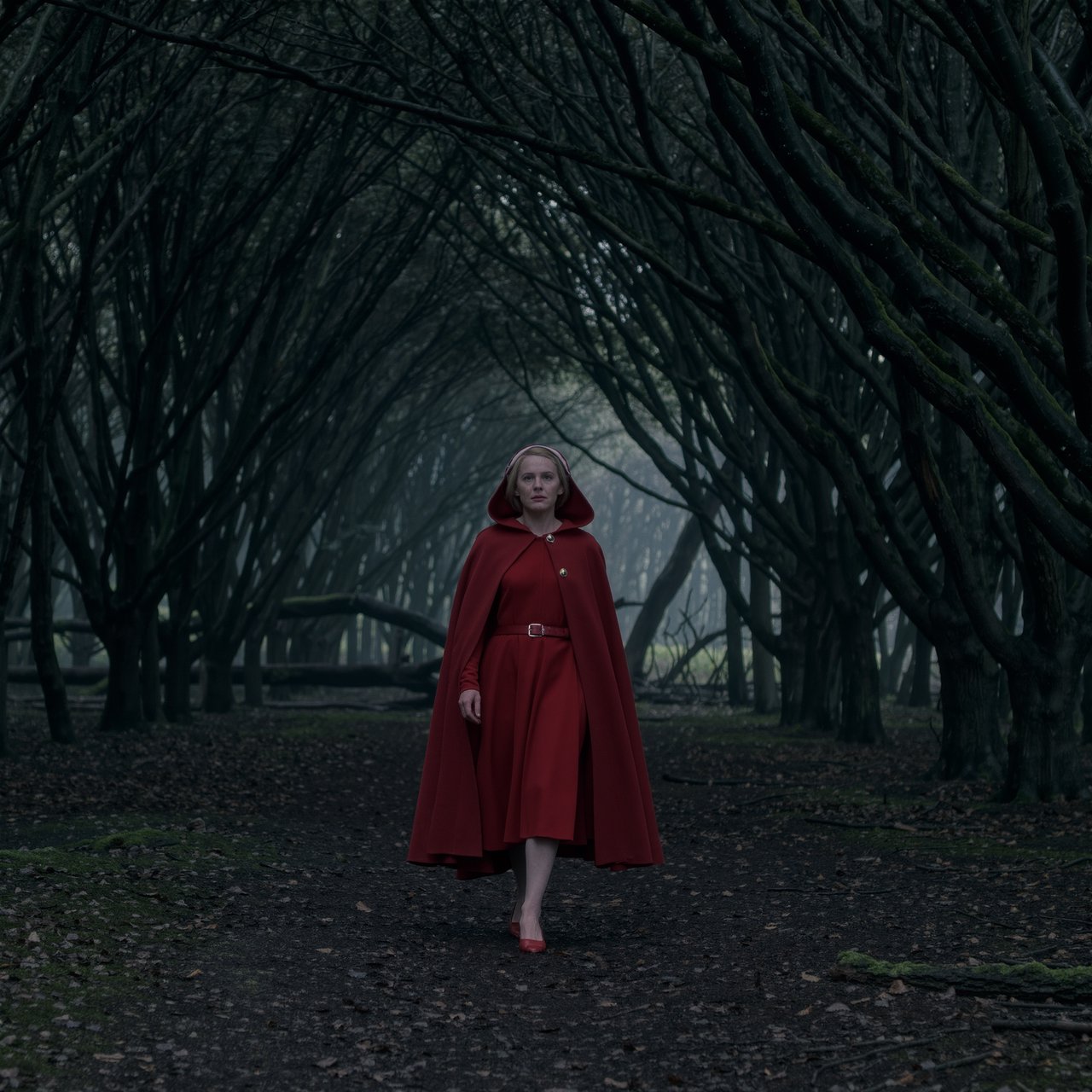 Medium shot at eye level: 1960s vintage film aesthetic. An adult woman with long, blonde hair walks alone through a dark forest. She wears a red hooded cloak, with the hood pulled up and fastened at the neck by a silver buckle. Photorealistic 1960s Technicolor film grain; soft, shallow depth of field. — Kling v3 Omni