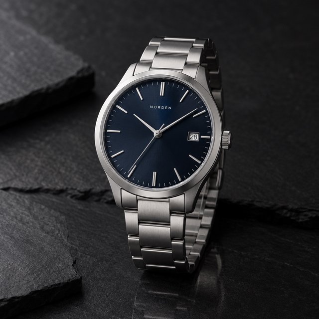 Product shot of a minimalist steel wristwatch with a navy dial on dark slate, single softbox from the upper left, subtle reflection. — GPT Image 2.5 Sunburst