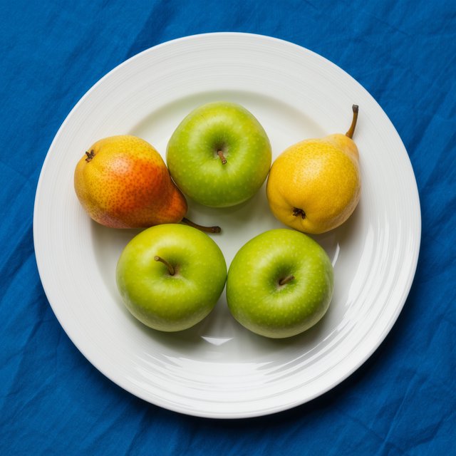 Exactly three green apples and two yellow pears on a white plate, the plate on a blue tablecloth, nothing else on the table. — Kling v3 Omni