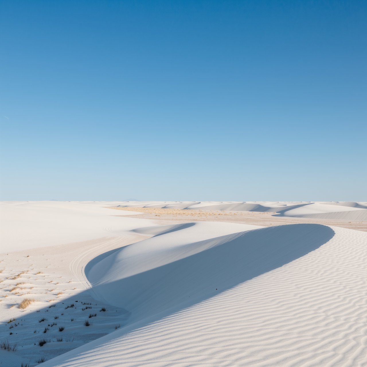 A pale gypsum dune field beneath a wind-brushed, cloudless midday sky, fine sand streaming over steep ridges; delicate ripple patterns and scattered salt-tolerant grasses sharpen the foreground as dunes soften toward a distant basin. — Kling v3 Omni