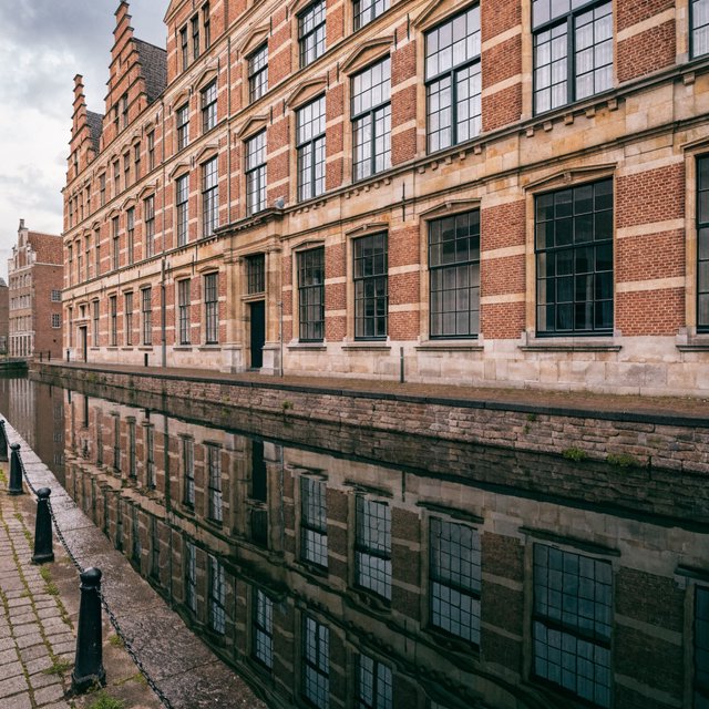 Exterior of a Dutch Renaissance canal-side archive, with warm red brick, pale stone bands, stepped gables, and tall sash windows; soft overcast light reveals the masonry, viewed from the opposite quay, with convincing structure and precise architectural lines. — Recraft v4