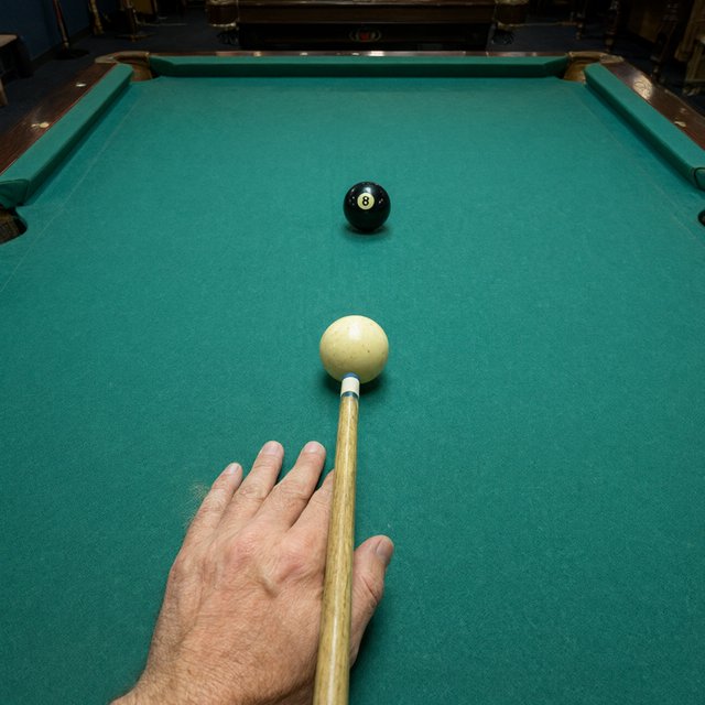 First-person perspective of an adult pool player’s left hand holding the cue, aiming the white cue ball at the black 8-ball and intending to pocket it in the center pocket. — Qwen Image 3.0