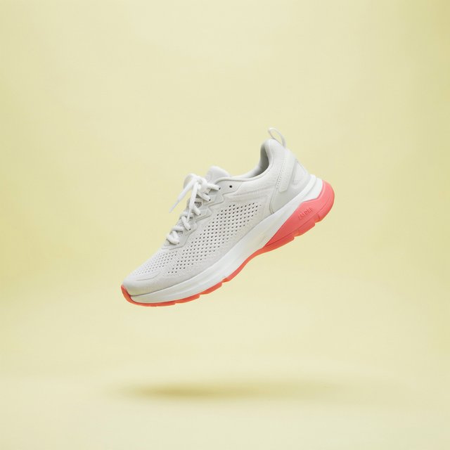 A white running sneaker with a coral sole floating at a slight angle over a pastel yellow background, studio lighting, no shadow on the backdrop. — Ideogram v4