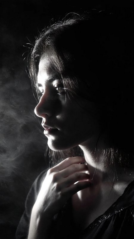Profile portrait of a woman in dramatic side lighting with smoke.