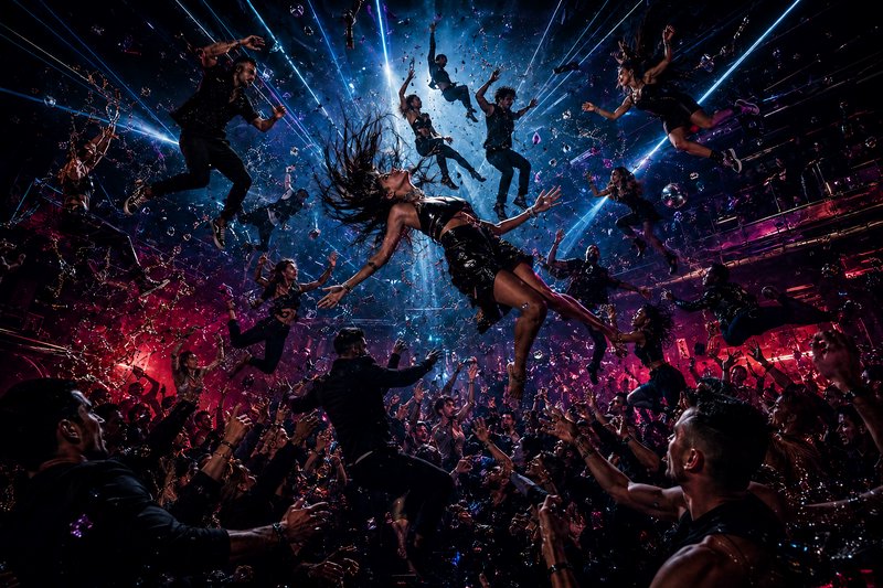 Crowd surfing in a vibrant nightclub with dancers, bright blue and pink lights, and splashes.