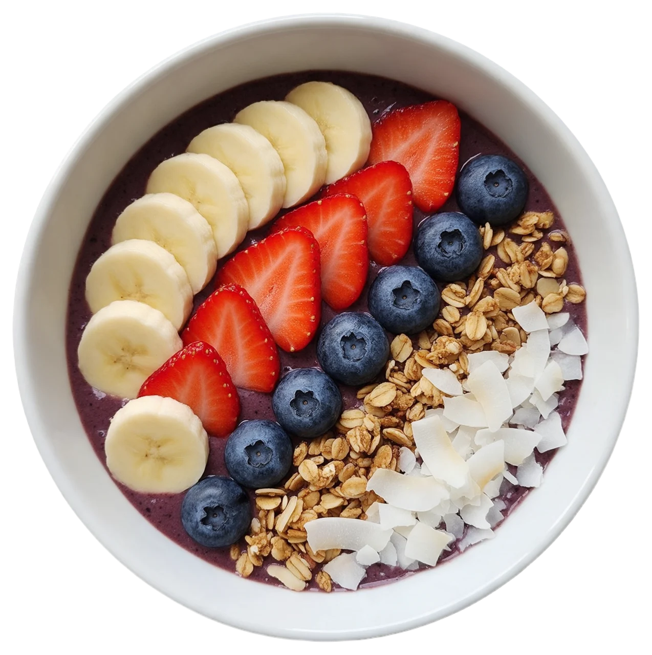 Top down view of a white ceramic acai bowl topped with arranged fresh fruit, granola and coconut flakes