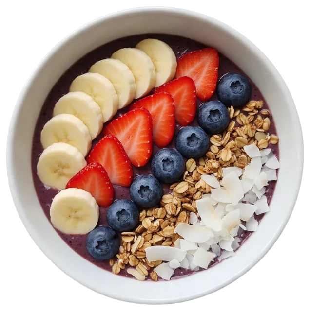 Top down view of a white ceramic acai bowl topped with arranged fresh fruit, granola and coconut flakes