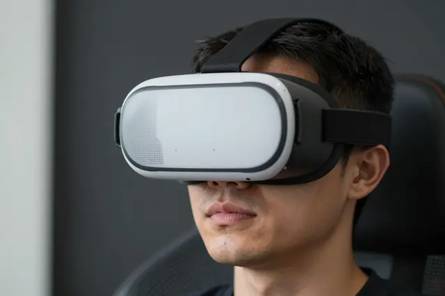 Close-up of an adult man wearing an unbranded VR headset while seated indoors.