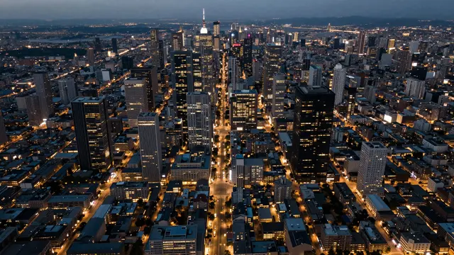 High angle aerial view of a dense downtown city grid lit with warm street and building lights at twilight