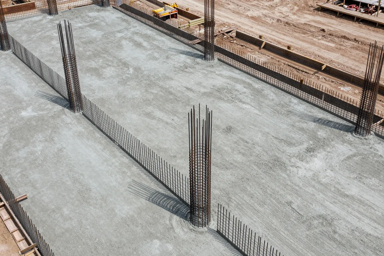 High angle view of a construction site with fresh poured concrete and exposed rebar columns