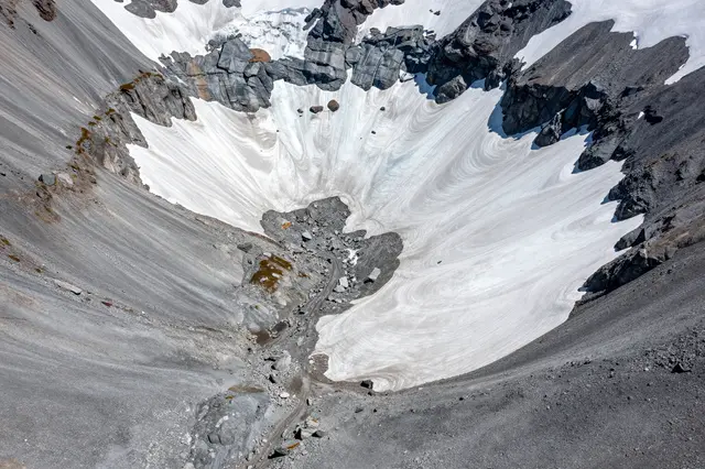 Aerial overhead view of a rocky glacial cirque with lingering snow and gray scree slopes