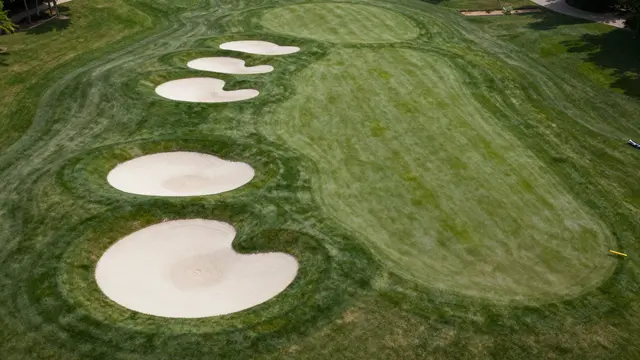 High angle aerial view of a golf course fairway lined with curved white sand bunkers under daylight