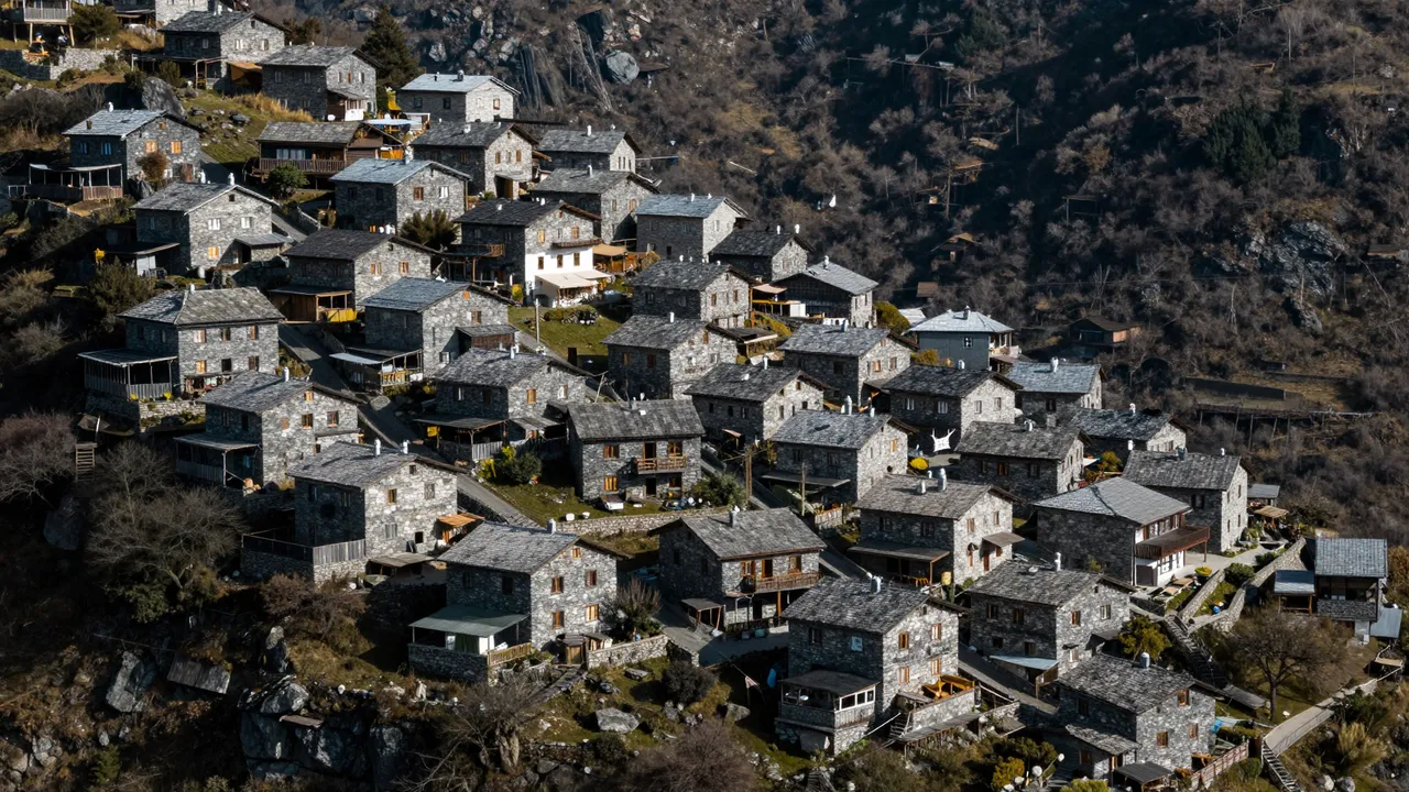 Aerial view of clustered stone houses built along a high mountain ridge under bright sunlight