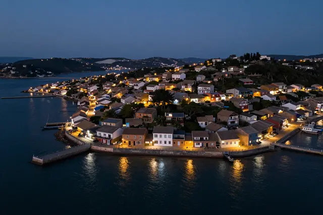 Aerial view of an illuminated small coastal village along a calm waterfront at twilight