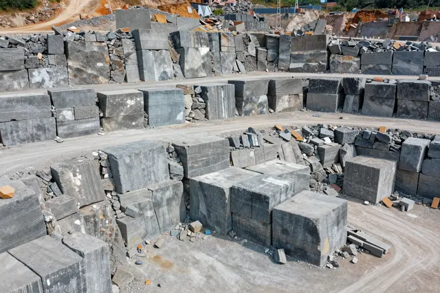 Aerial view of a working quarry stacked with large cut stone blocks and dirt access roads