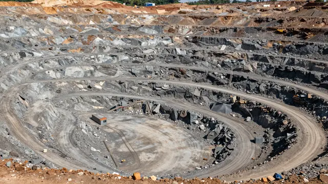 High-angle aerial view looking down into a large terraced open-pit mine with winding access roads