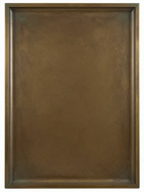 Full frame close-up of a raised rectangular antique bronze surface with mottled brown and green patina