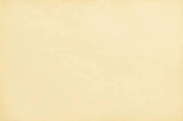 Full frame top view of a smooth pale yellowed old paper surface with subtle fibrous grain
