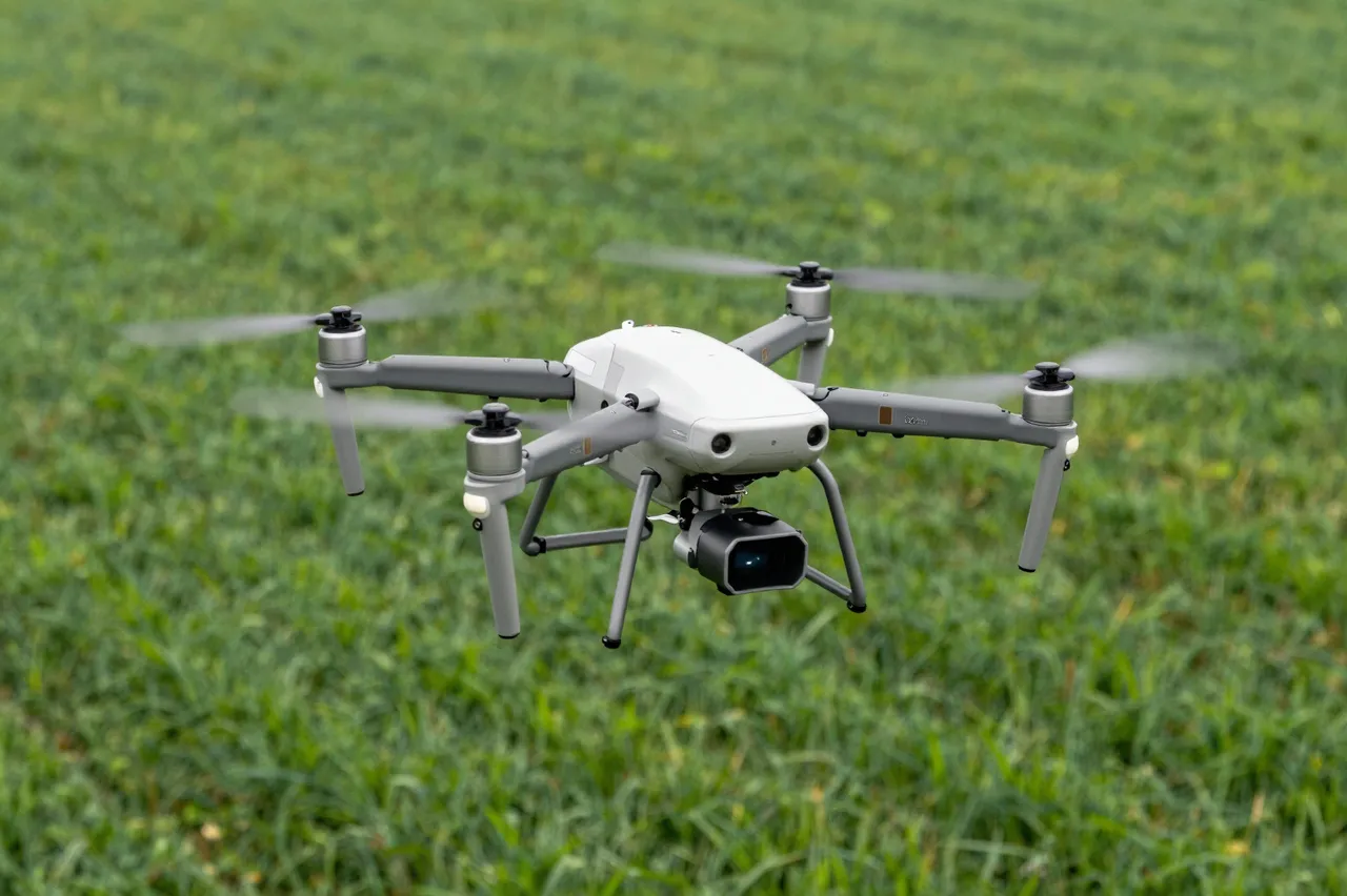 A quadcopter drone hovers mid-air above a lush green farm field with spinning blurred propellers