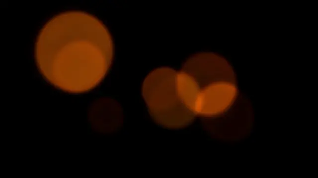 Soft sparse amber bokeh circles scattered across a solid pure black background