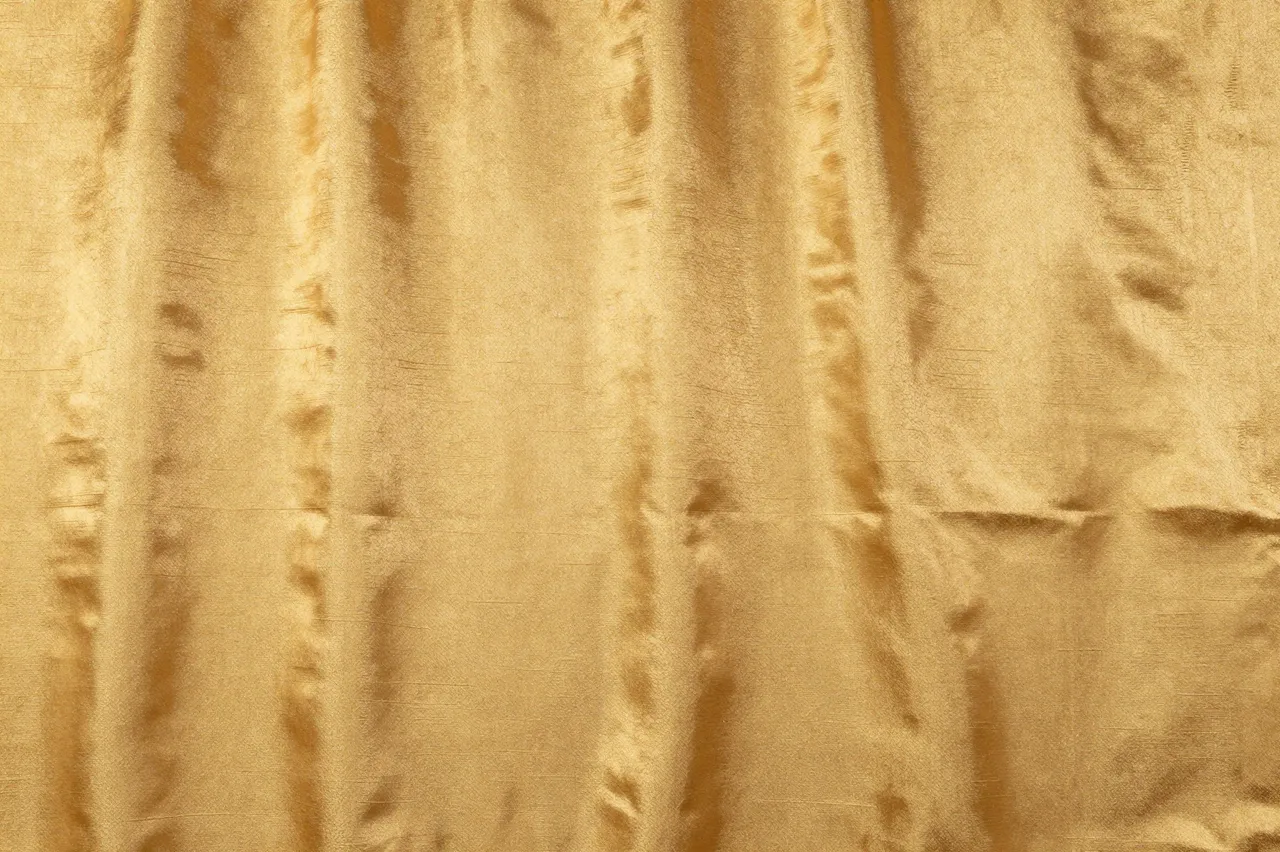 Full frame close-up of crinkled antique gold dupioni silk fabric with natural slubs and soft sheen