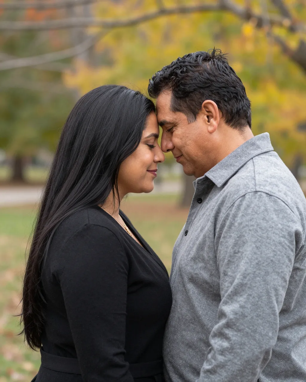 A Latino couple in their forties touch foreheads with closed eyes in an autumn park
