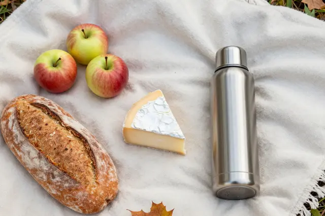 Flat lay of a fall picnic spread arranged on a soft off-white wool blanket outdoors