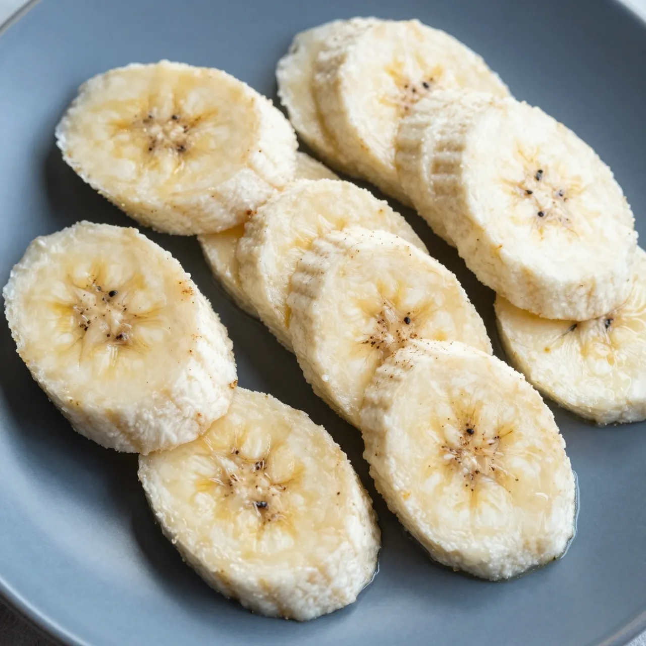 Top view of fresh banana slices sprinkled with spice arranged on a matte blue plate