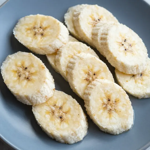 Top view of fresh banana slices sprinkled with spice arranged on a matte blue plate