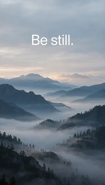 Misty layered mountain range at dawn with clean white text reading "Be still." in the calm upper sky