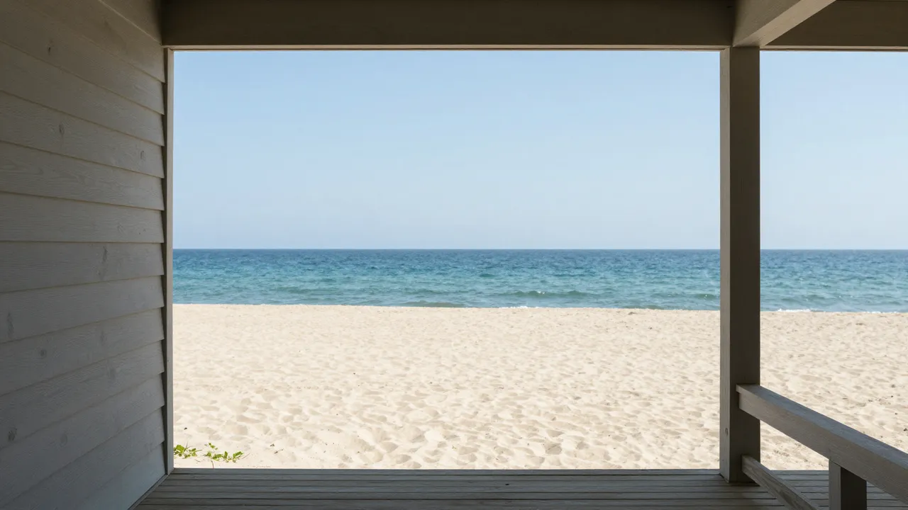 View from a wooden beach house porch looking out over a sandy beach to the calm turquoise ocean under a clear sky