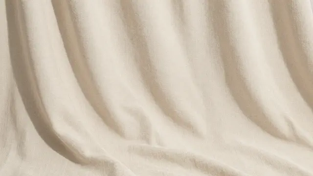 Soft draped beige linen fabric with gentle natural folds lit by warm daylight