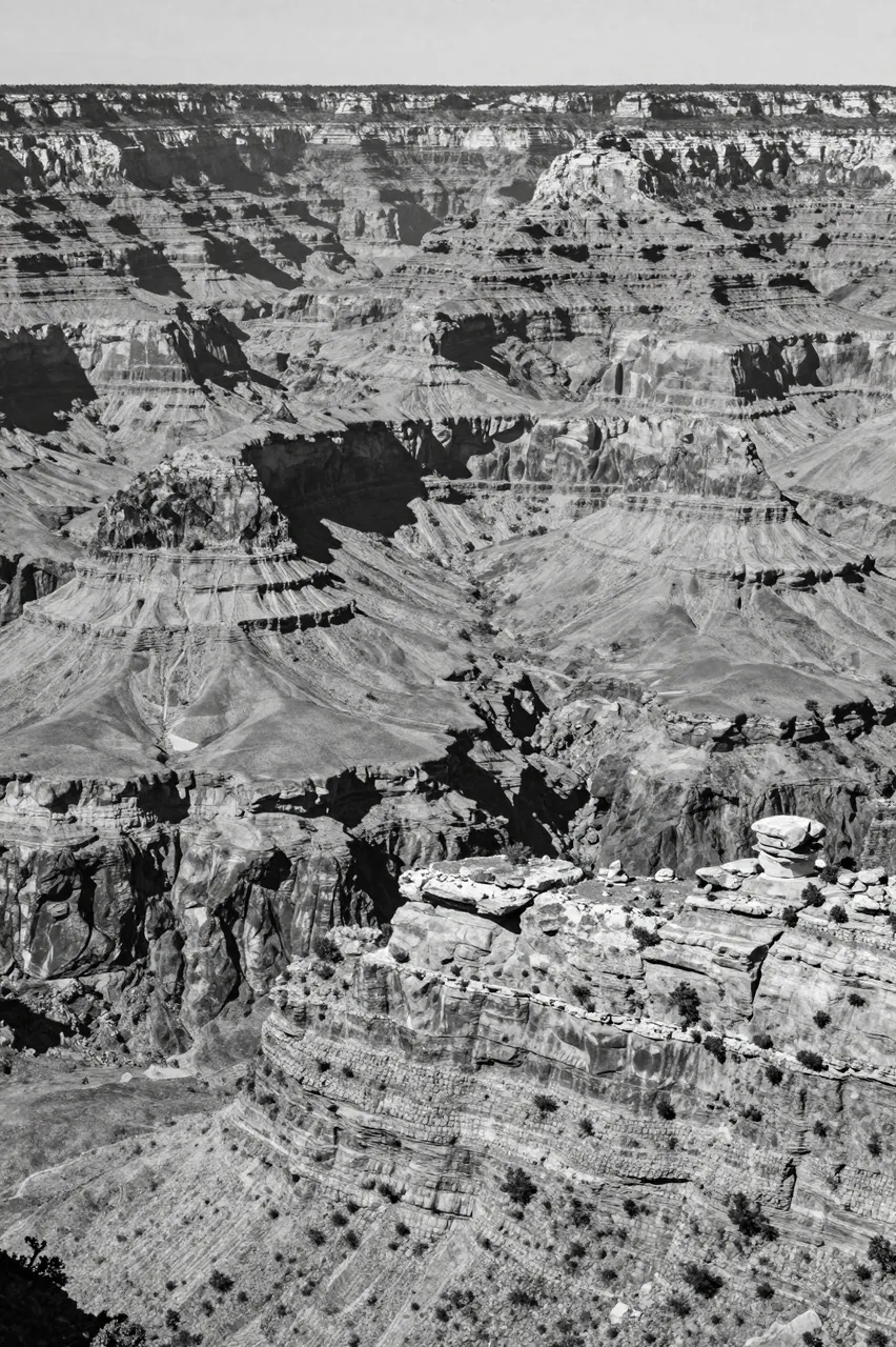 High angle black and white view of layered canyon rock formations under bright midday light