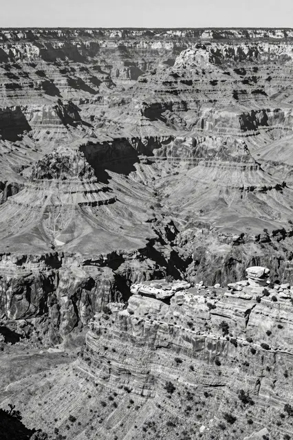 High angle black and white view of layered canyon rock formations under bright midday light