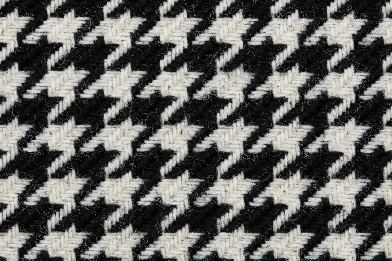 Full frame close-up of textured black and white houndstooth woven wool fabric with a soft fuzzy nap.
