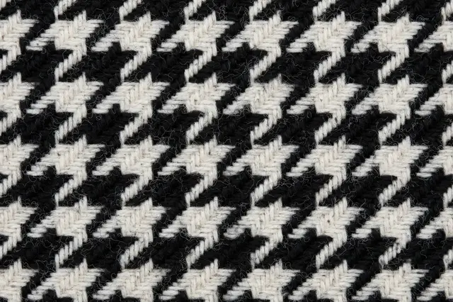 Full frame close-up of textured black and white houndstooth woven wool fabric with a soft fuzzy nap.