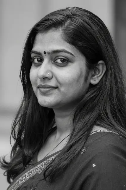 Monochrome close-up portrait of a South Asian woman with a nose ring and long hair, looking at the camera