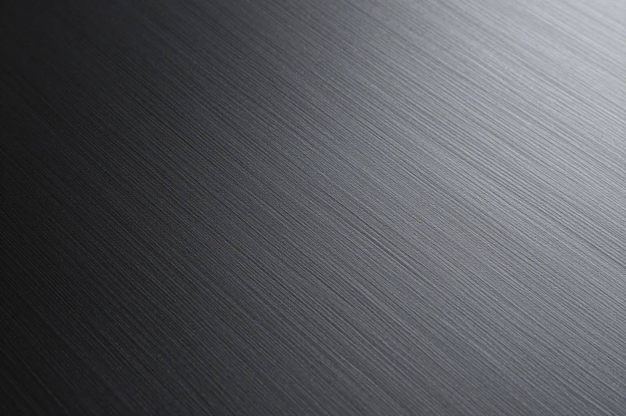 Full frame close-up of fine diagonal brushed lines across a smooth black anodized metal surface