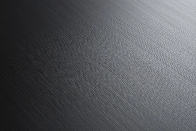 Full frame close-up of fine diagonal brushed lines across a smooth black anodized metal surface