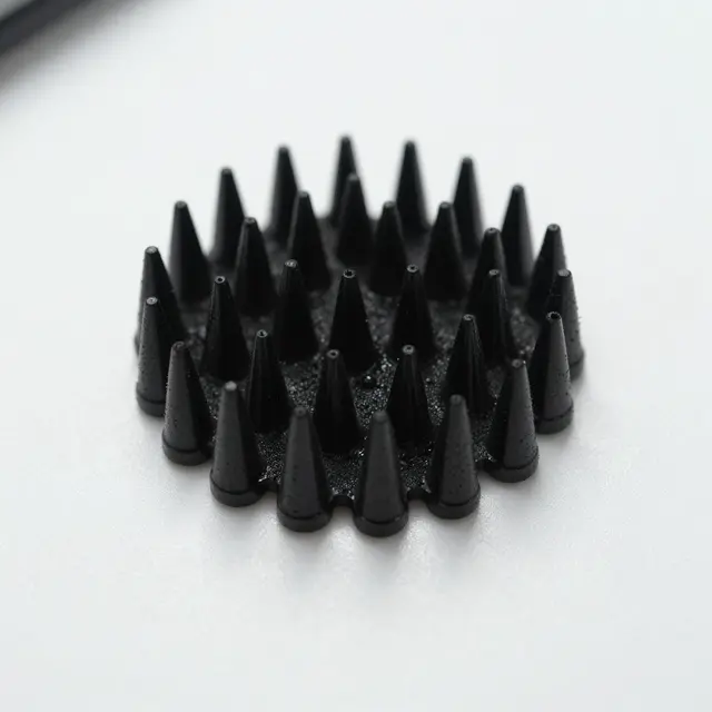Close-up of sharp black conical ferrofluid spikes arranged in a circle on a smooth white surface