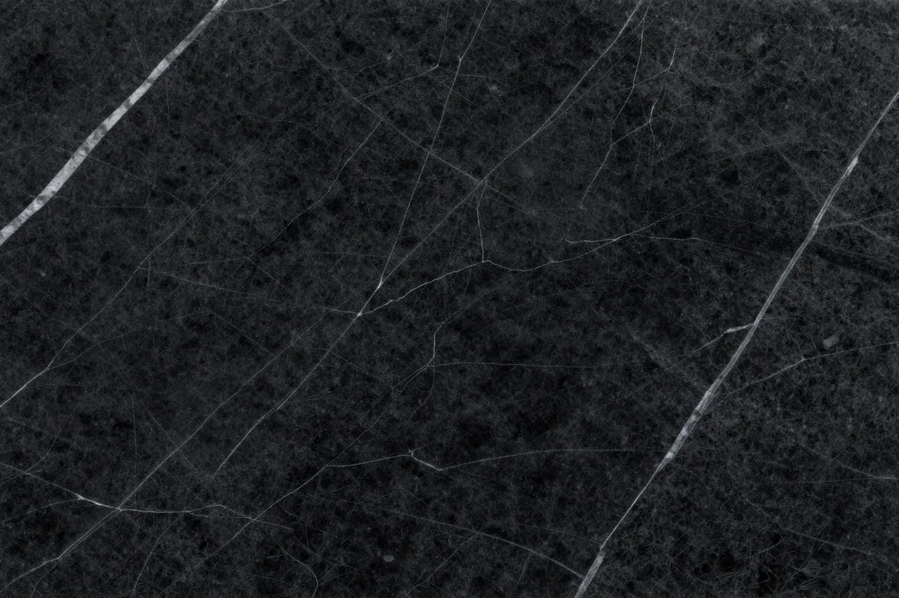 Close up view of a polished black marble surface with thin irregular white veining