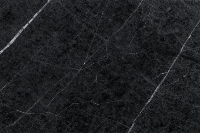 Close up view of a polished black marble surface with thin irregular white veining