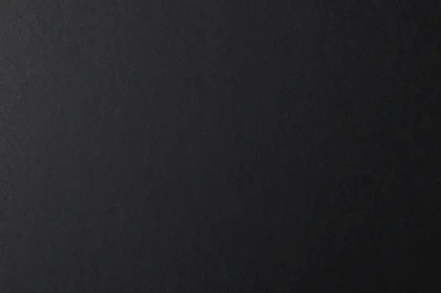 Top view of a matte black paper surface with subtle fine fibrous texture and full copy space