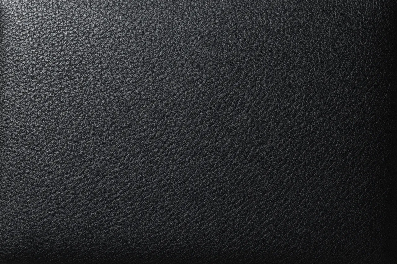 Full frame close-up of black pebbled leather with a subtle left-side sheen and fine grain detail