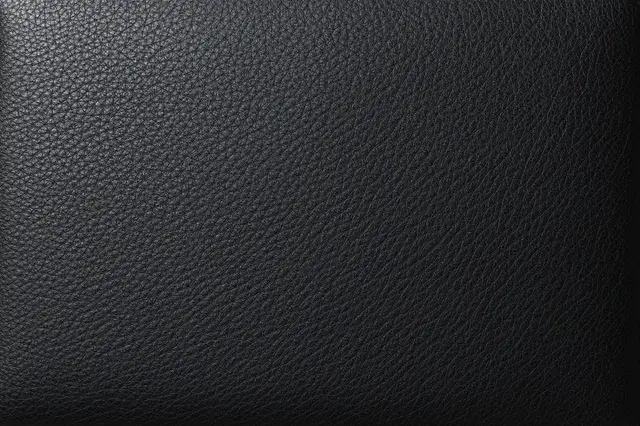 Full frame close-up of black pebbled leather with a subtle left-side sheen and fine grain detail