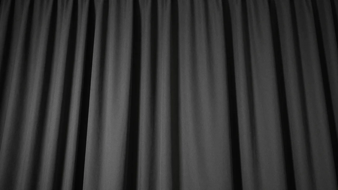 Dark pleated black stage curtain with soft vertical folds lit by subtle overhead lighting