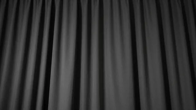 Dark pleated black stage curtain with soft vertical folds lit by subtle overhead lighting