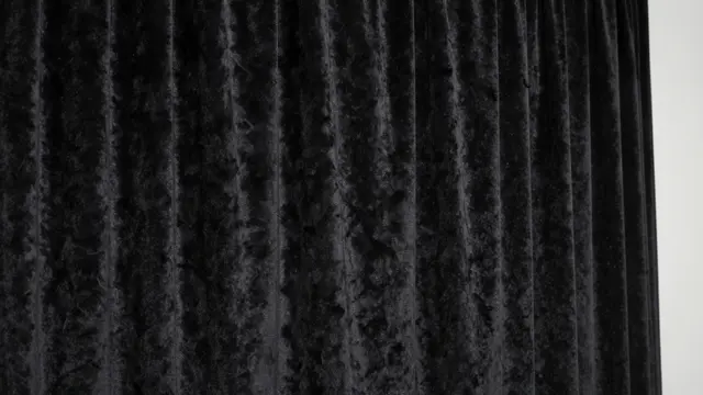 Pleated black velvet fabric catches soft light with a narrow plain white edge on the right side