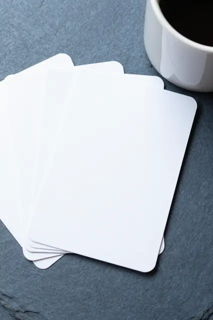 Fanned blank white cards sit beside a white coffee mug on a slate blue surface with empty copy space