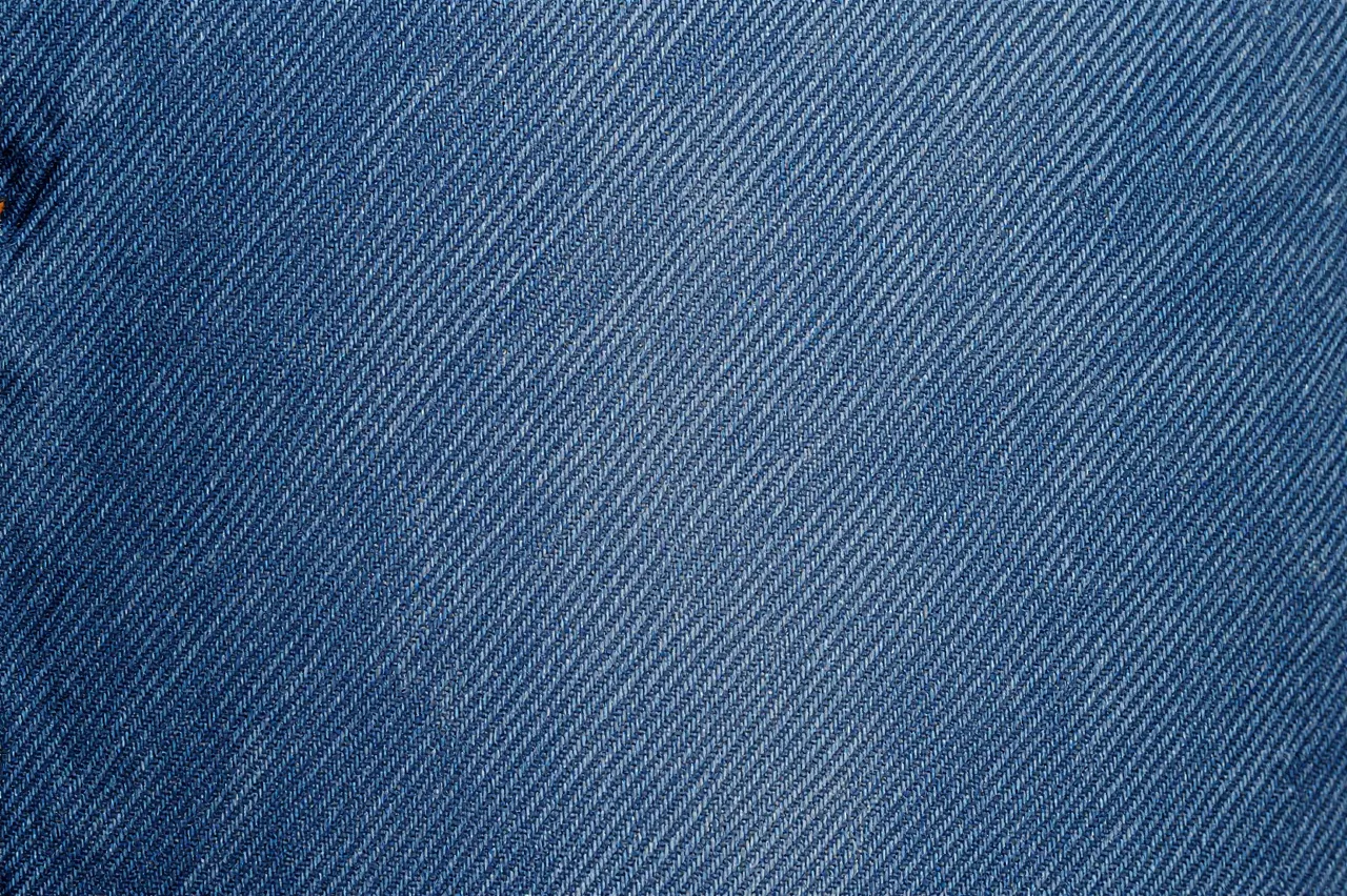 Close-up view of the diagonal woven texture of medium blue denim fabric